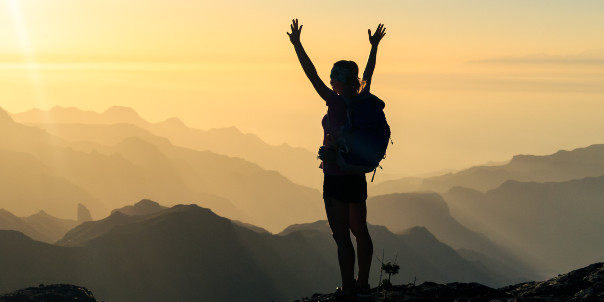 Woman on top of mountain celebrating.