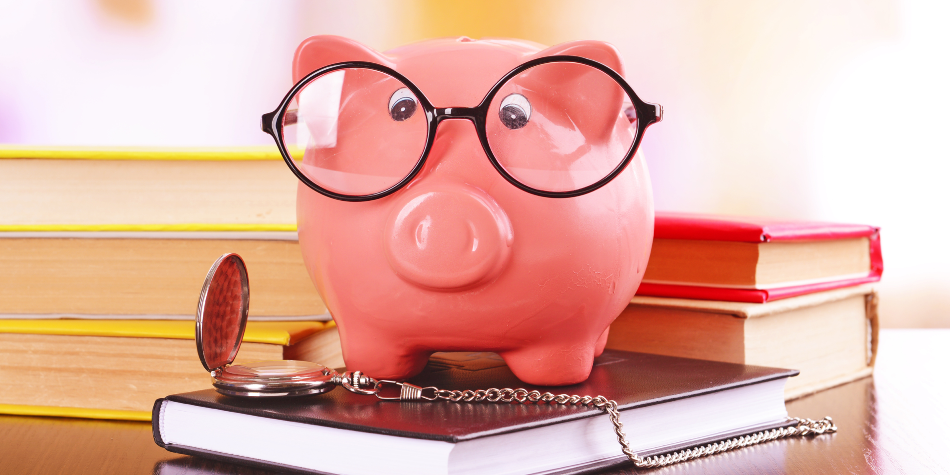 Pig piggy bank with glasses on a stack of book.