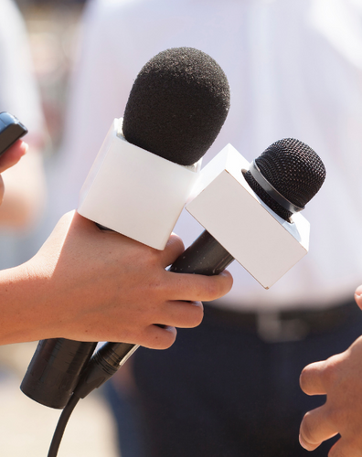 Reporters holding up microphone to conduct an interview.