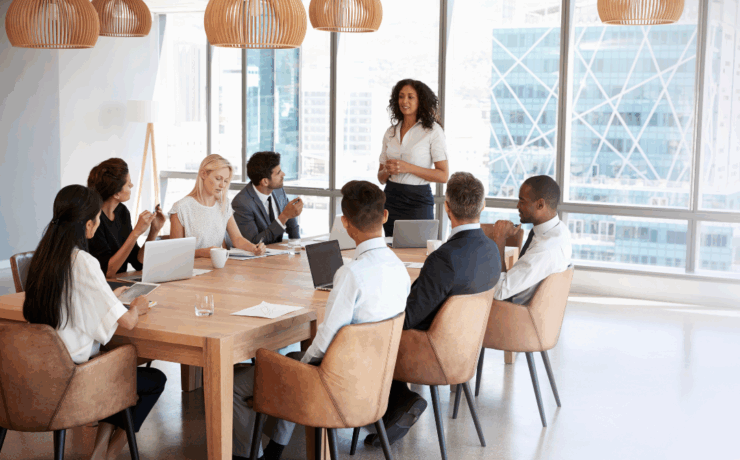 A confident nonprofit leader stands to present in a boardroom filled with diverse professionals, symbolizing strategic planning, collaboration, and forward-thinking fundraising practices.